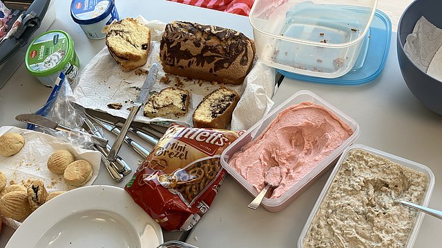 Auf einem Tisch stehen Teller und Tupperdosen mit unterschiedlichen Speisen